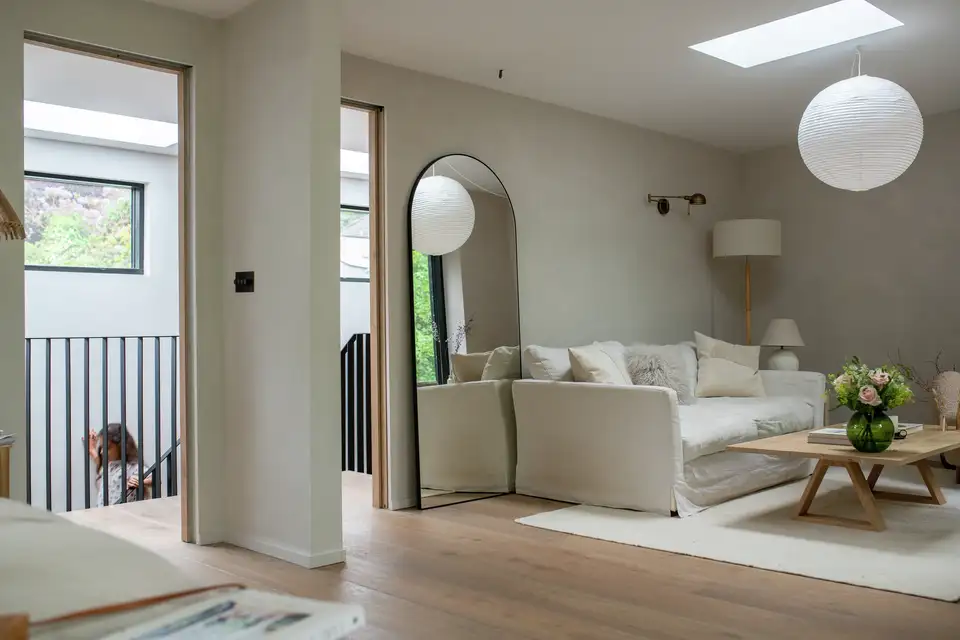 Soggiorno con finestra per tetti piani VELUX e specchio che riflette e amplifica la luce naturale