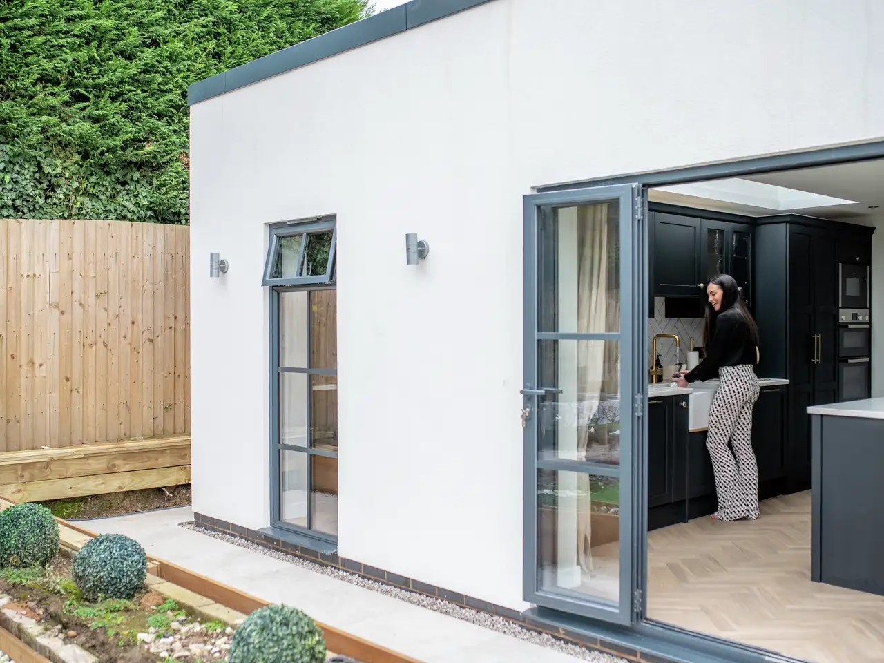 Modern kitchen extension with black cabinetry and large glass doors.
