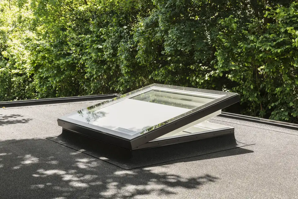 fenêtre de toit plat VELUX ouverte, entourée de verdure