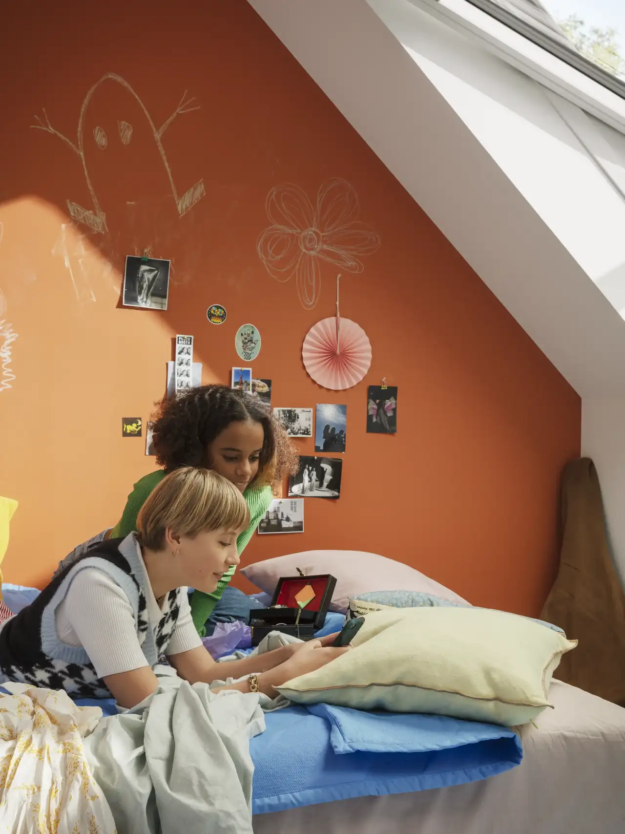 Deux filles sont allongées sur leur lit d'adolescent sous la pente du toit  | Magazine VELUX