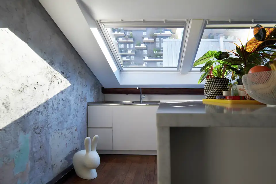 Cuisine sous combles avec un plan de travail situé sous de larges fenêtres de toit VELUX. 