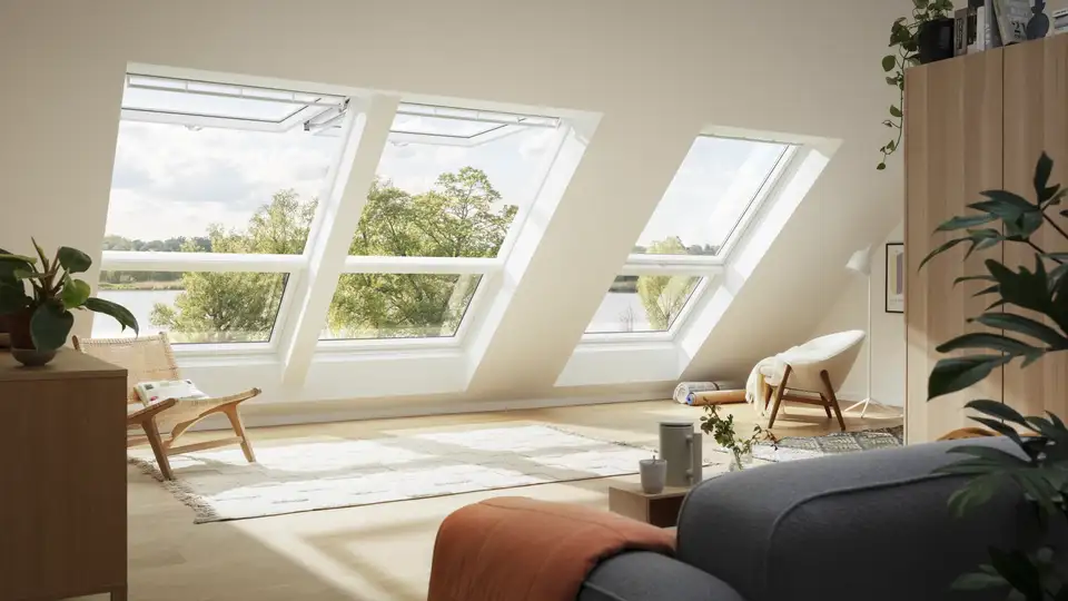 Salon sous combles avec trois fenêtres de toit VELUX, dont deux ouvertes pour la ventilation 