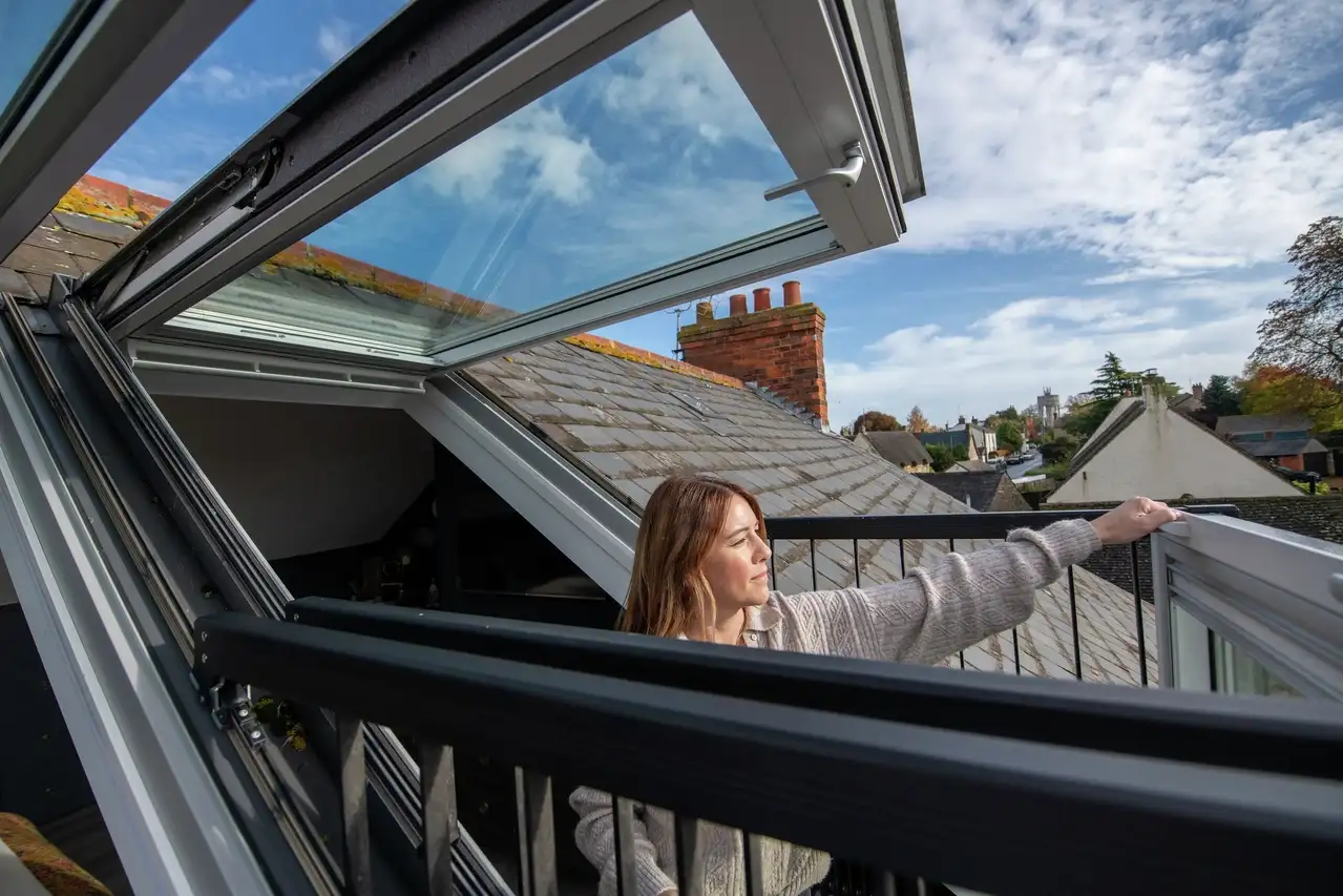 Open VELUX roof window in loft, view of sky and rooftops 
