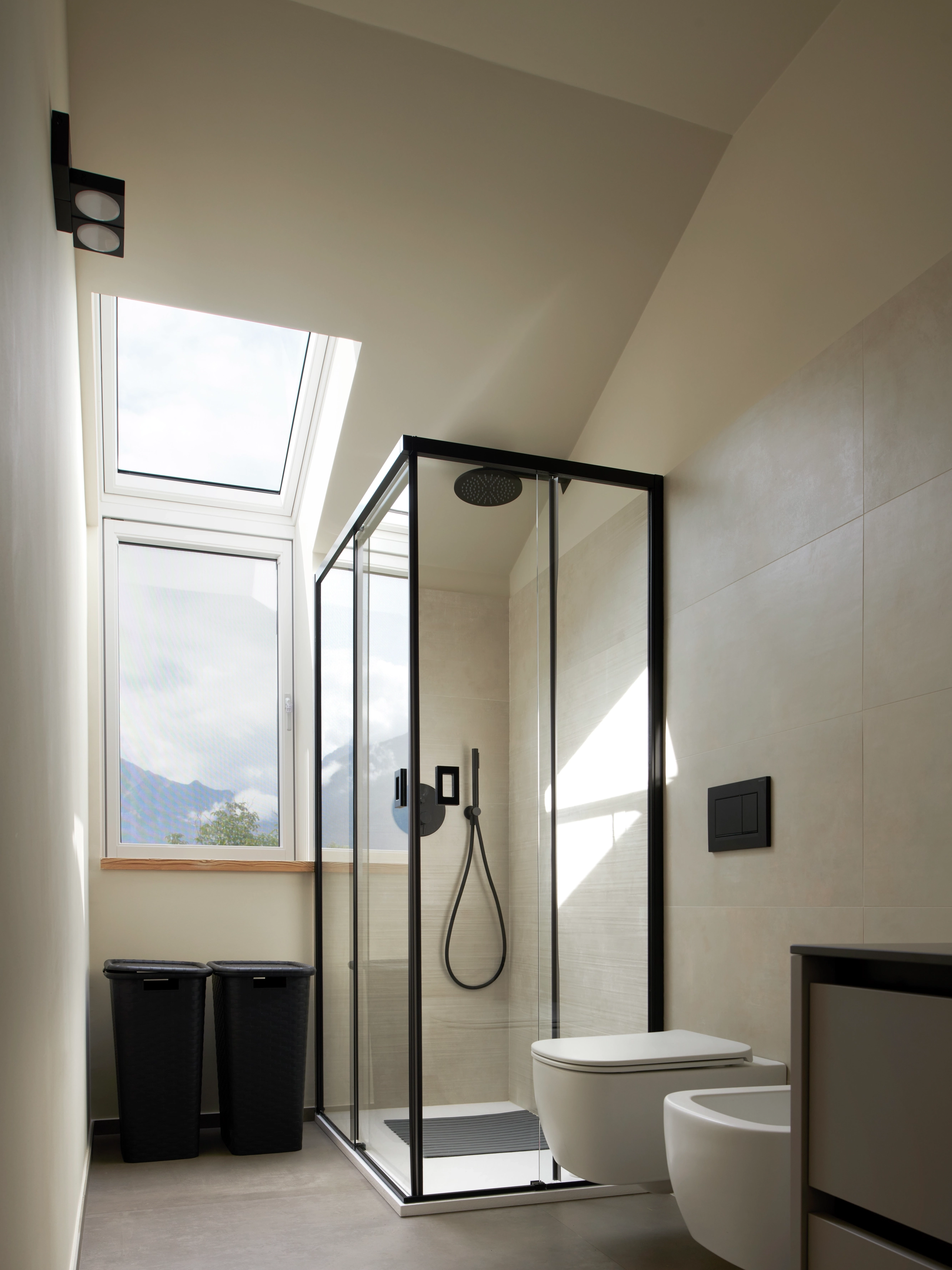 Bathroom with sloped ceiling and VELUX roof window, modern shower and toilet.