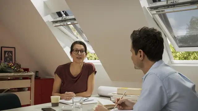 Nő és férfi beszélgetnek nyitott tetőtéri ablakok mellett