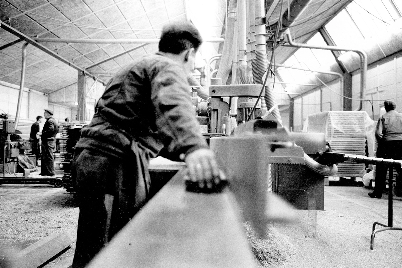 Schwarz-Weiß-Foto von Arbeitern in einer aktiven Industriewerkstatt mit Maschinen.