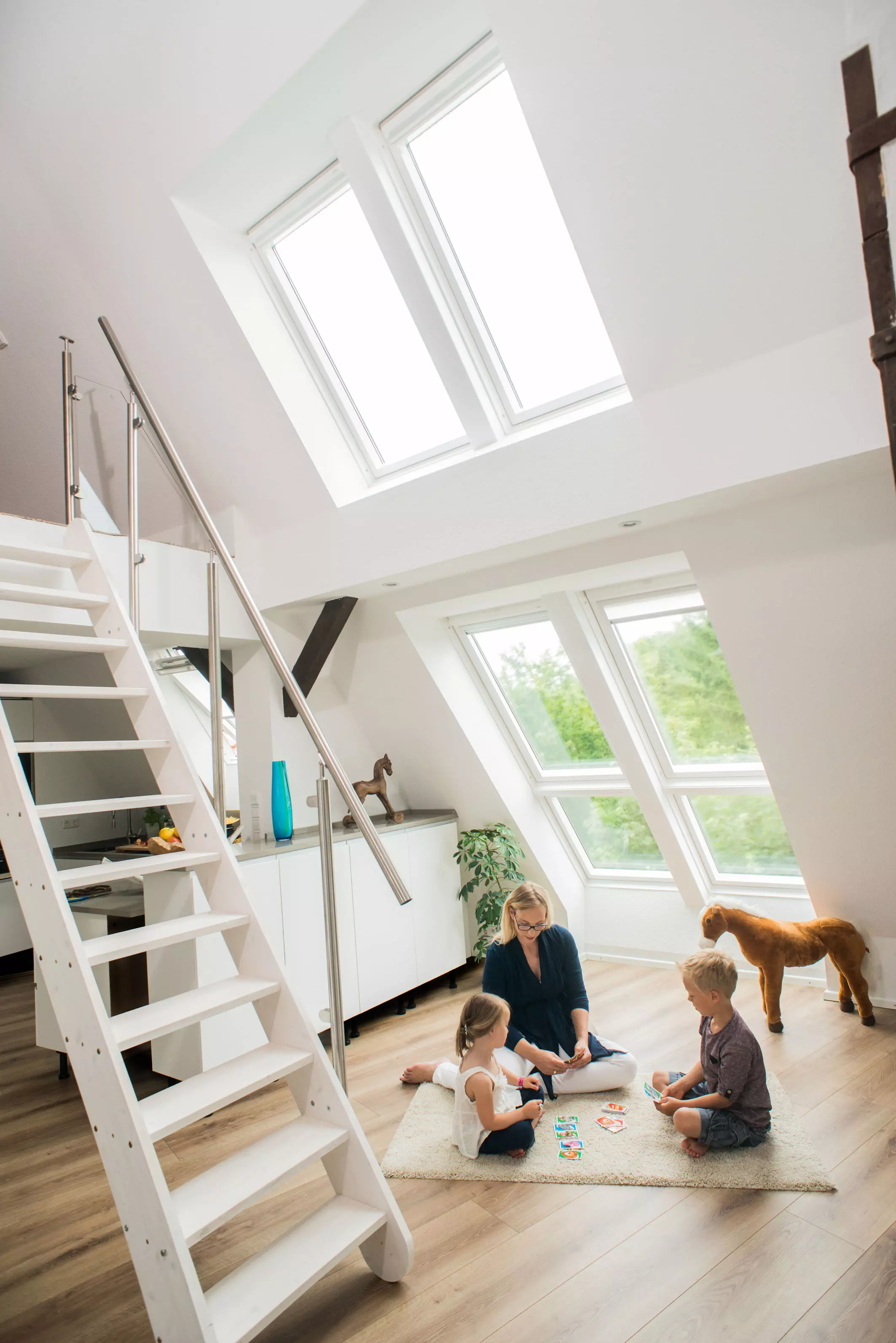 Frau und zwei Kinder spielen unter großer Dachfensterlösung | VELUX Magazin