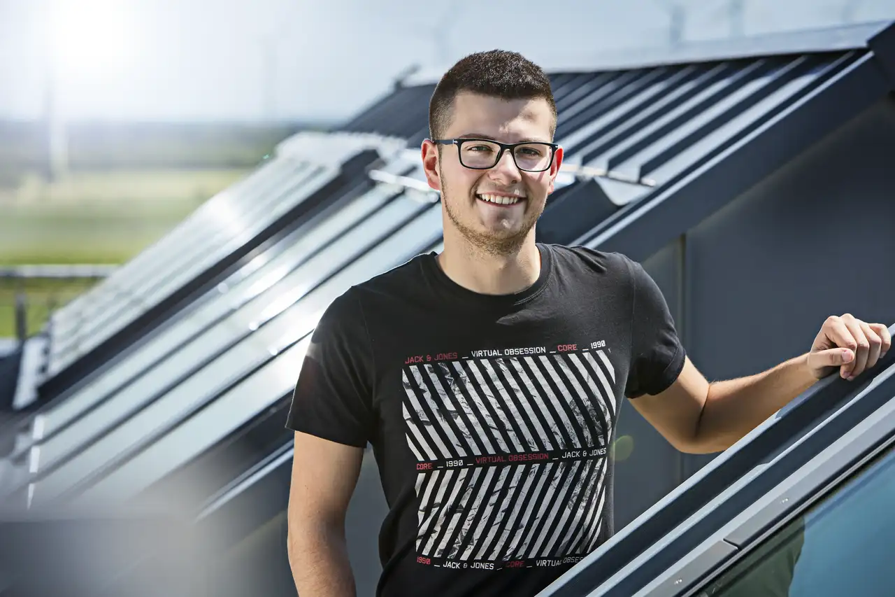 Mladý muž drží okno VELUX a usmieva sa.