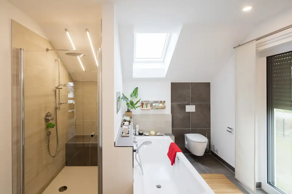Salle de bain moderne avec douche éclairée par des LED et lumière naturelle d’une fenêtre de toit. 