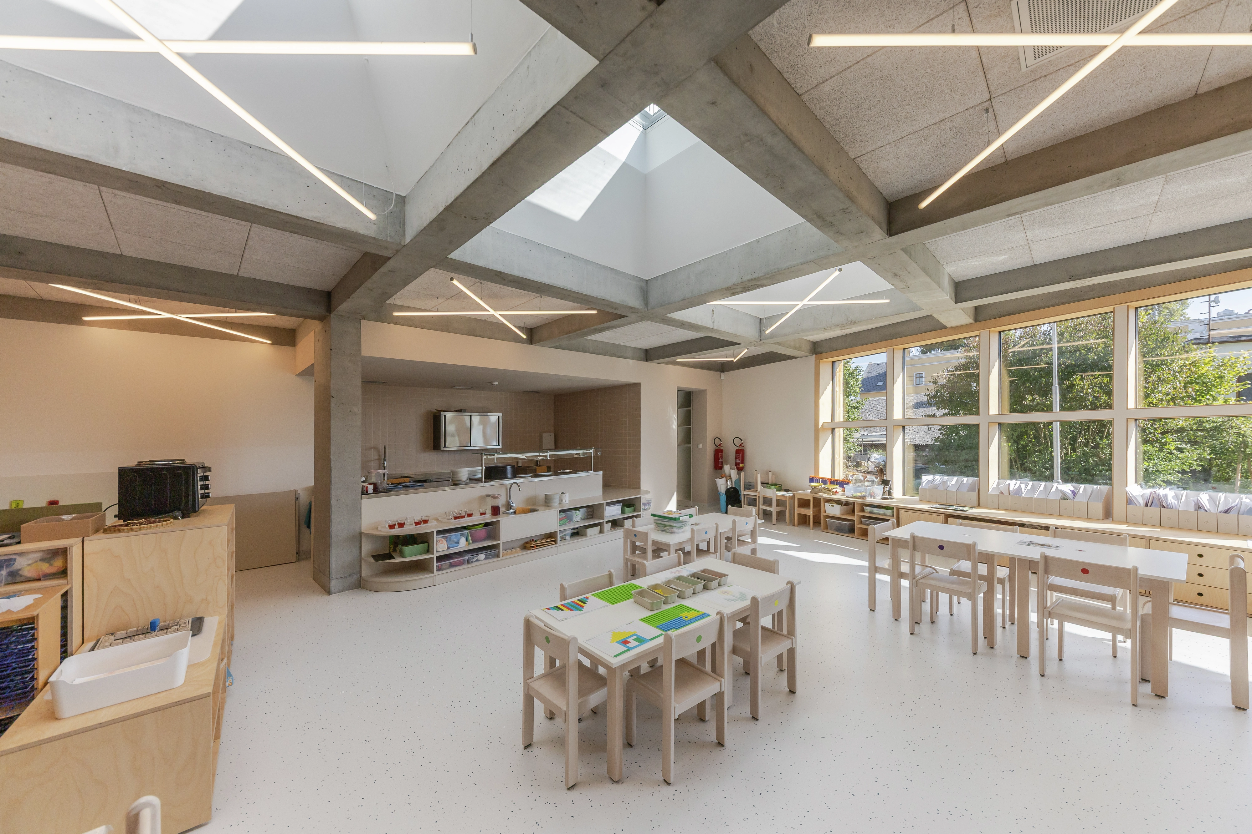Classroom with large windows and skylights, child-sized furniture.