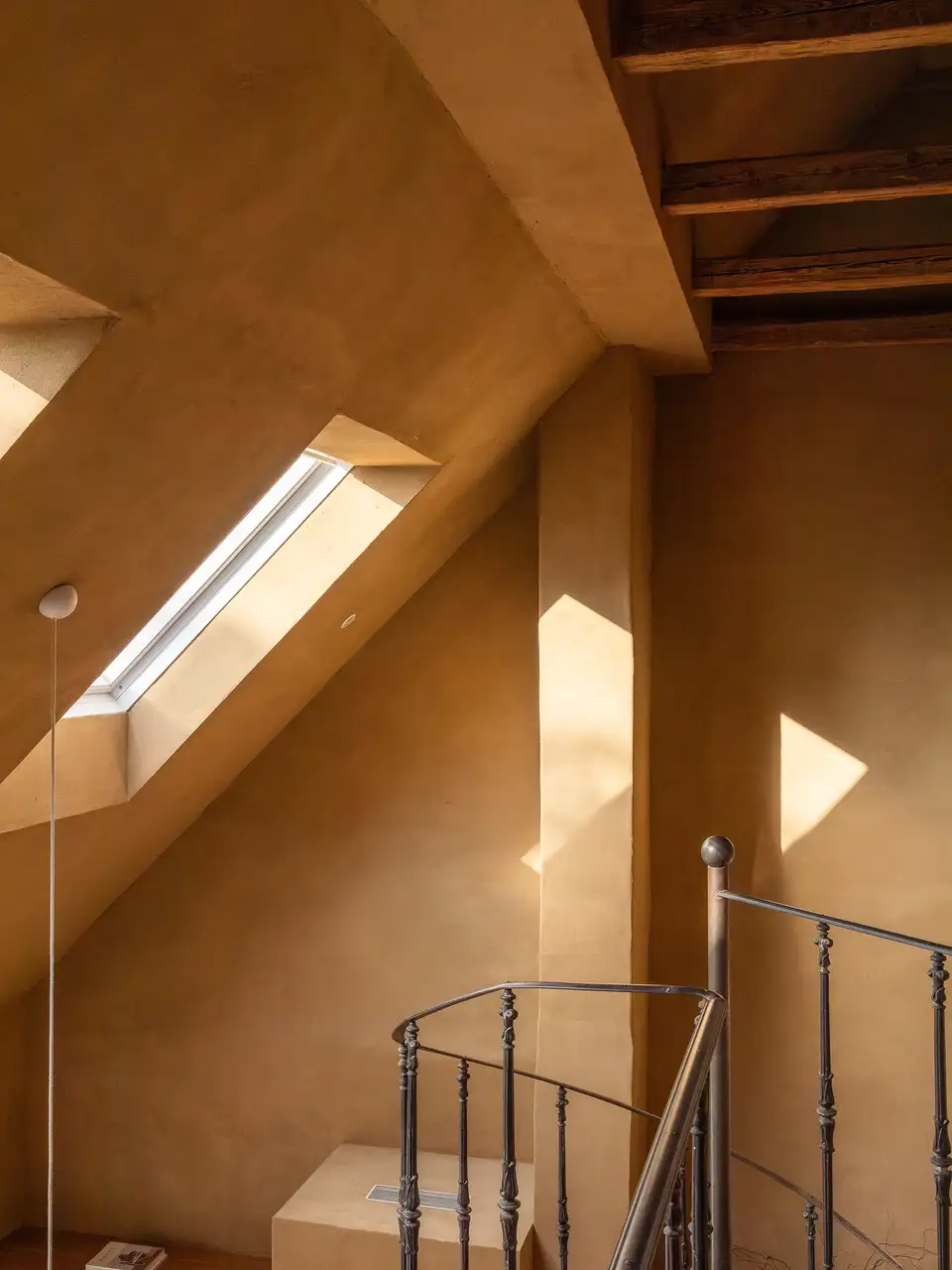 Luce che entra da una finestra per tetti e filtra attraverso una scala verso i piani inferiori