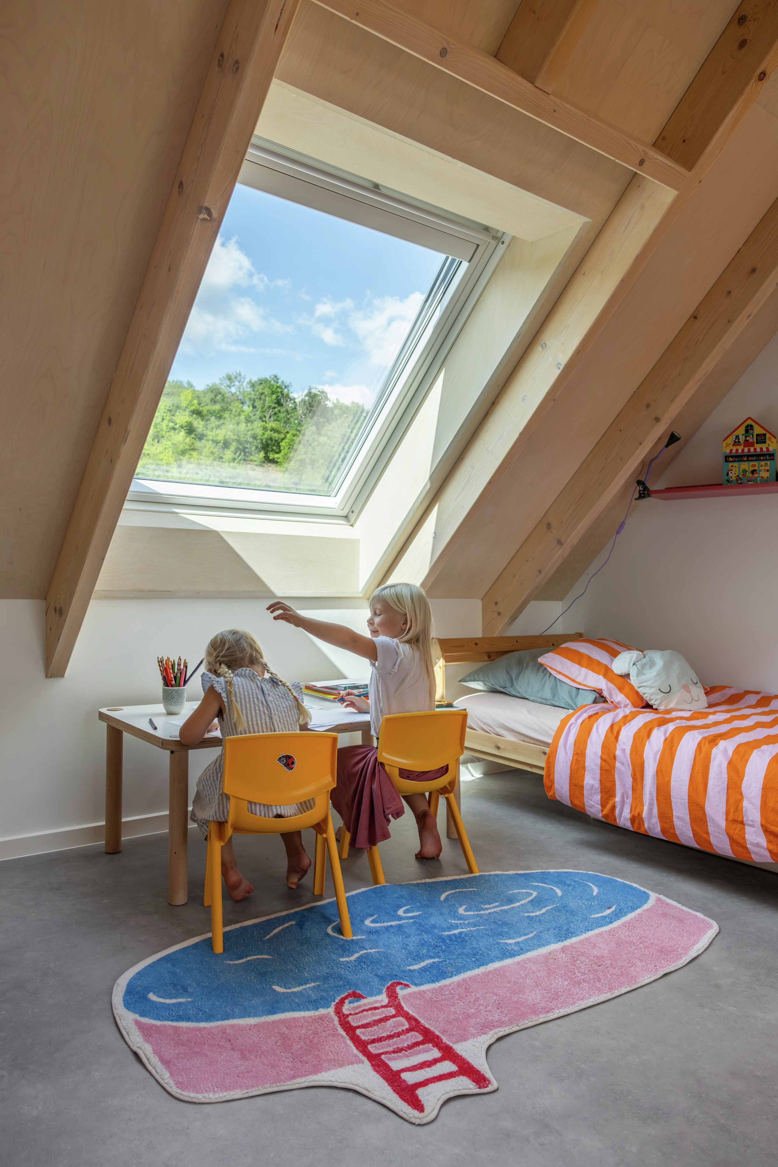 Attic kids room with sloped ceiling and VELUX roof window, bright and playful.