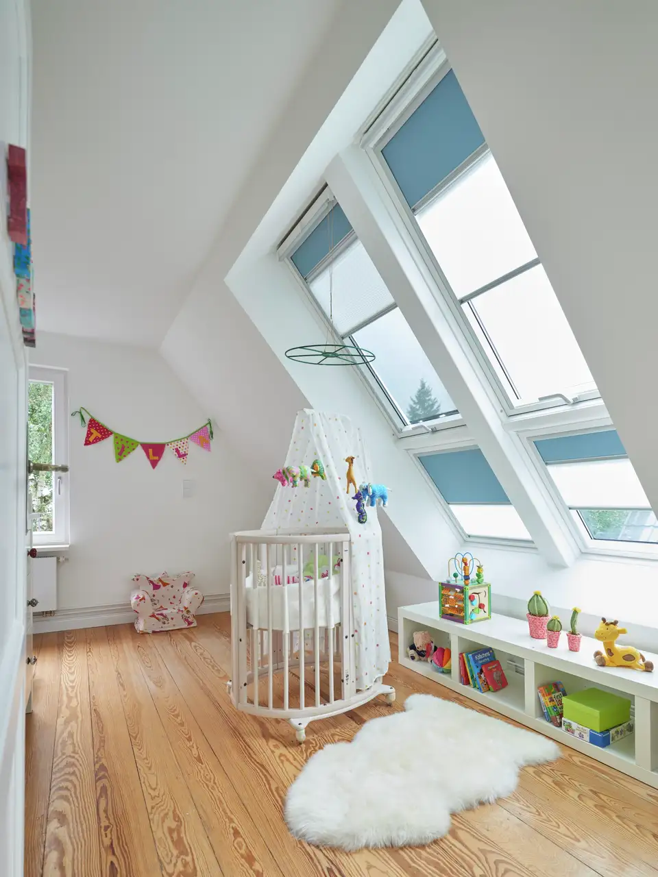 Chambre de bébé lumineuse avec fenêtres de toit VELUX, décorée avec des tons naturels et du mobilier adapté.