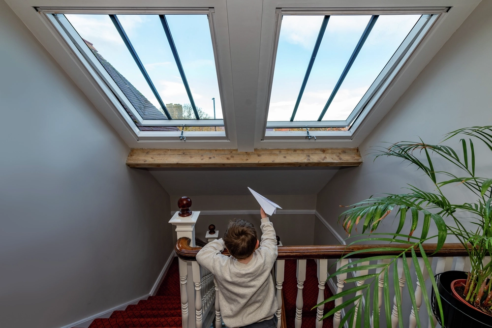 kid playing with paperplain below velux heritage roof windows