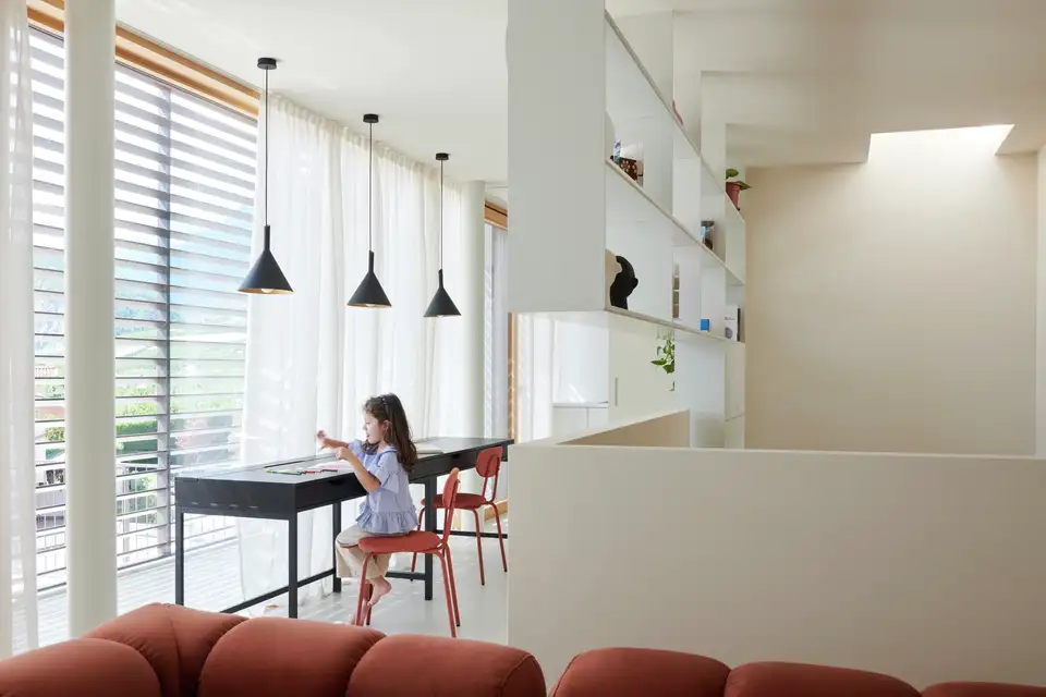 "Een klein meisje maakt haar huiswerk aan haar bureau, verlicht door natuurlijk daglicht." 