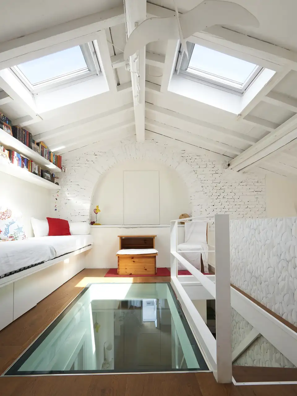 Camera da letto in mansarda con due bambini che giocano sulla porzione di pavimento in vetro