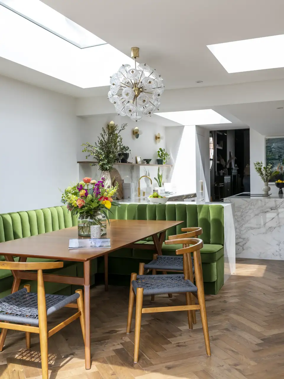 sala da pranzo con tavolo e sedie in legno, panchina foderata in verde, lampadario eclettico e finestre per tetti