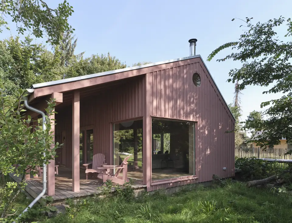  maison de montagne avec toit en pente, larges ouvertures et véranda nichée dans la verdure