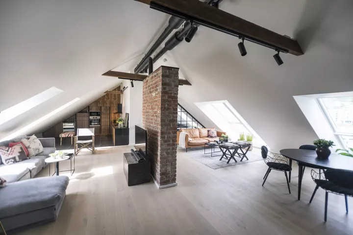 Wohnzimmer im Spitzboden mit einer Steinmauer als räumliches Trennelement | VELUX Magazin