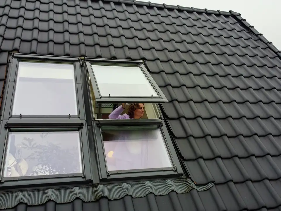 Dak met open VELUX dakraam, donkere keramische dakpannen zichtbaar.