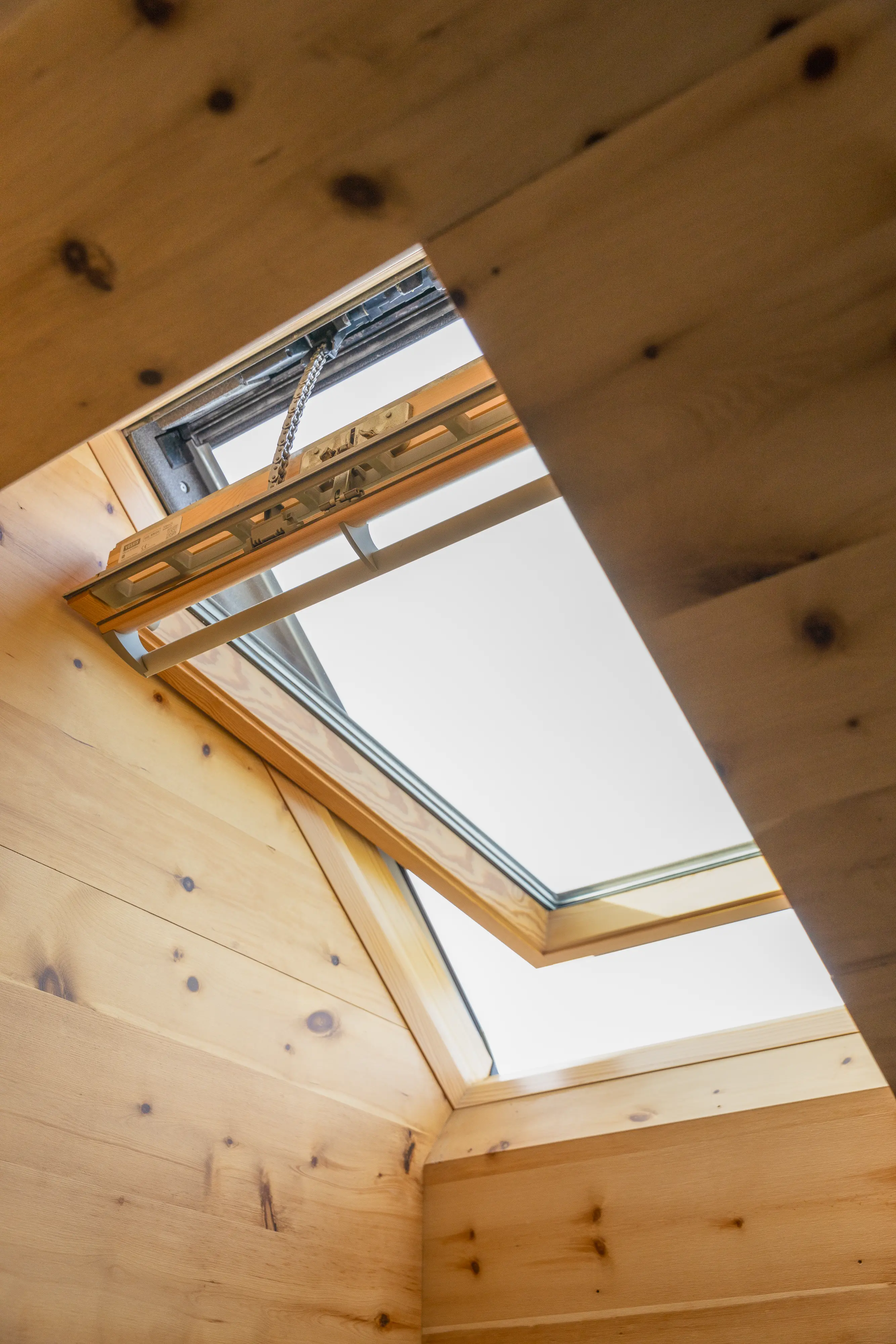 Nyitott, fa belső felületű VELUX tetőablak egy burkolt tetőtéri helyiségben, amely jól illusztrálja a fa tetőablakok rendszeres tisztítását és karbantartását.