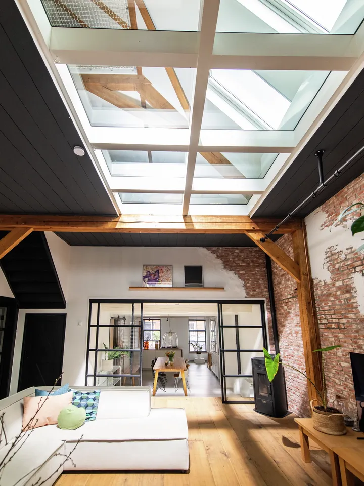 Lichtdurchfluteter Wohnraum mit angrenzendem Koch- und Essbereich, getrennt durch verglasten Raumteiler | VELUX Magazin