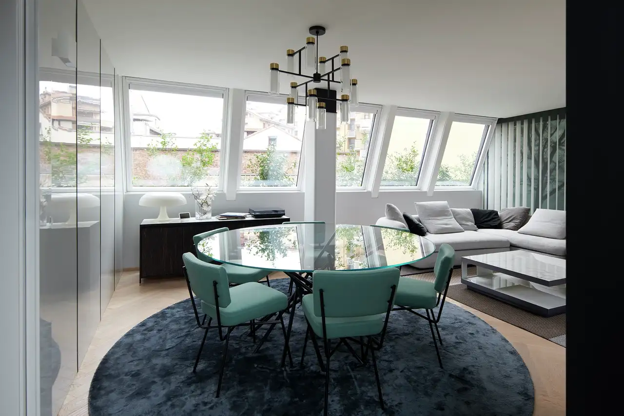 Zona living in mansarda con tavolo tondo, siede e divano che riceve luce naturale abbondante da cinque finestre per tetti VELUX affiancate.