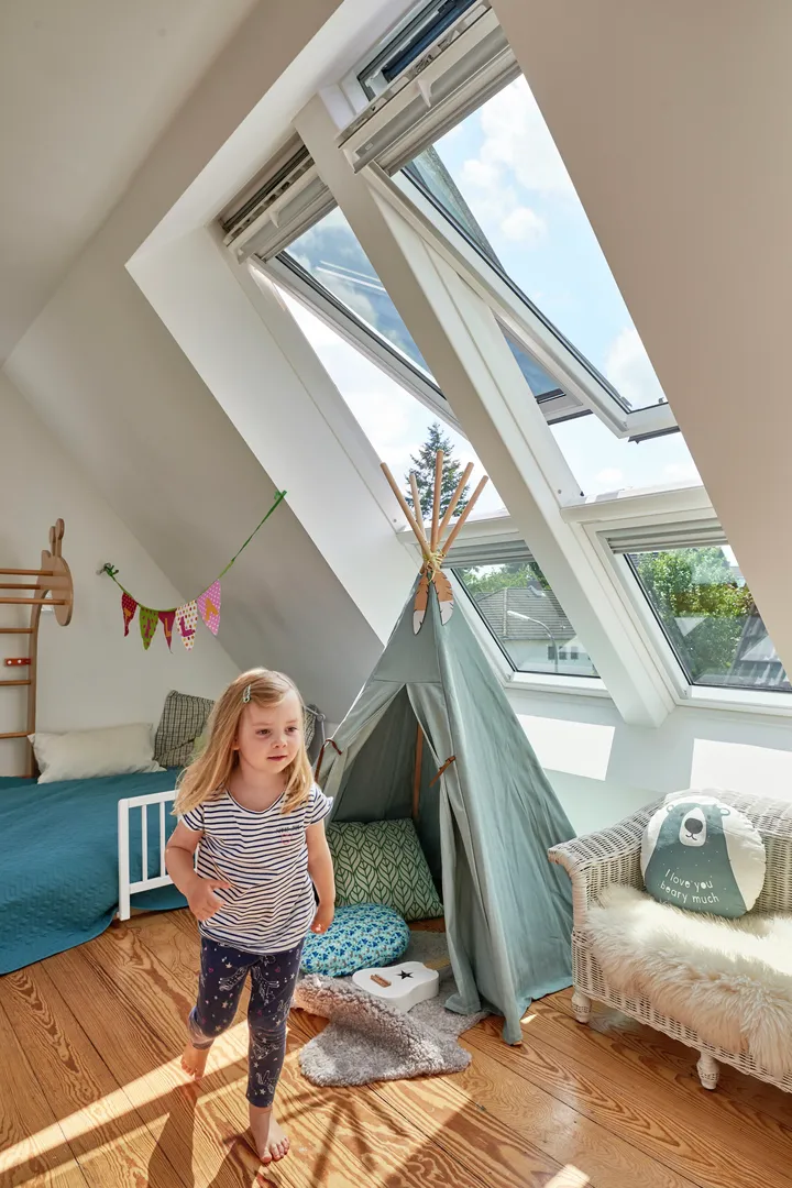 Geräumiges Dachboden-Homeoffice mit VELUX Dachflächenfenster und modernen weißen Möbeln.