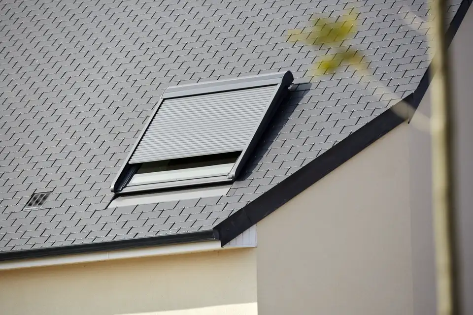 Buitenaanzicht van een dak met een VELUX dakvenster en gedeeltelijk neergelaten rolluik 