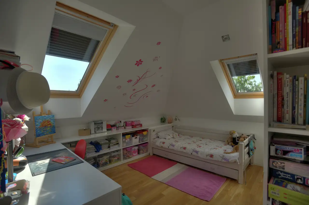 Kinderslaapkamer onder een dak, uitgerust met twee VELUX dakvensters met rolluiken om licht en warmte tegen te houden