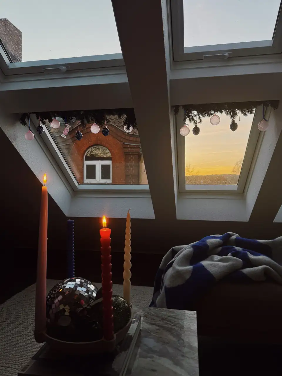 Finestra per tetti VELUX chiusa con ghirlanda e palline natalizie rosa e blu appese alla barra di manovra