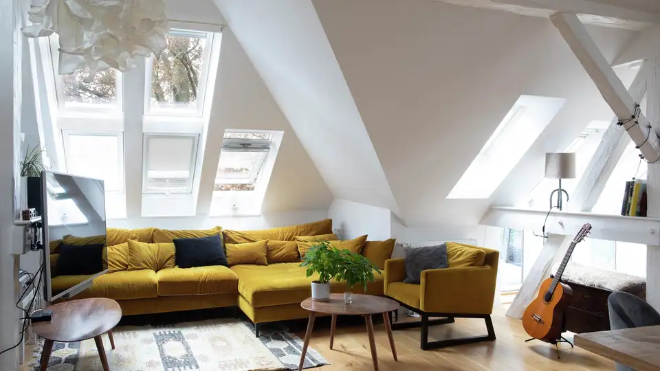 Séjour avec canapé en velours de style rétro, baigné de lumière naturelle grâce à plusieurs fenêtres de toit VELUX.