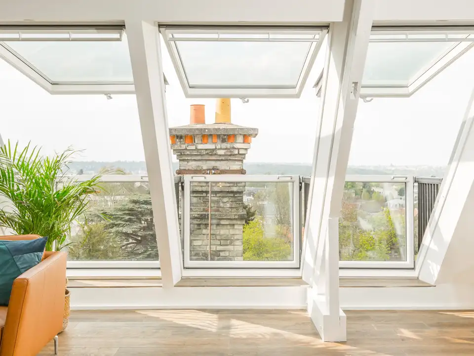 Attic room with VELUX roof windows, leather sofa, and panoramic view.