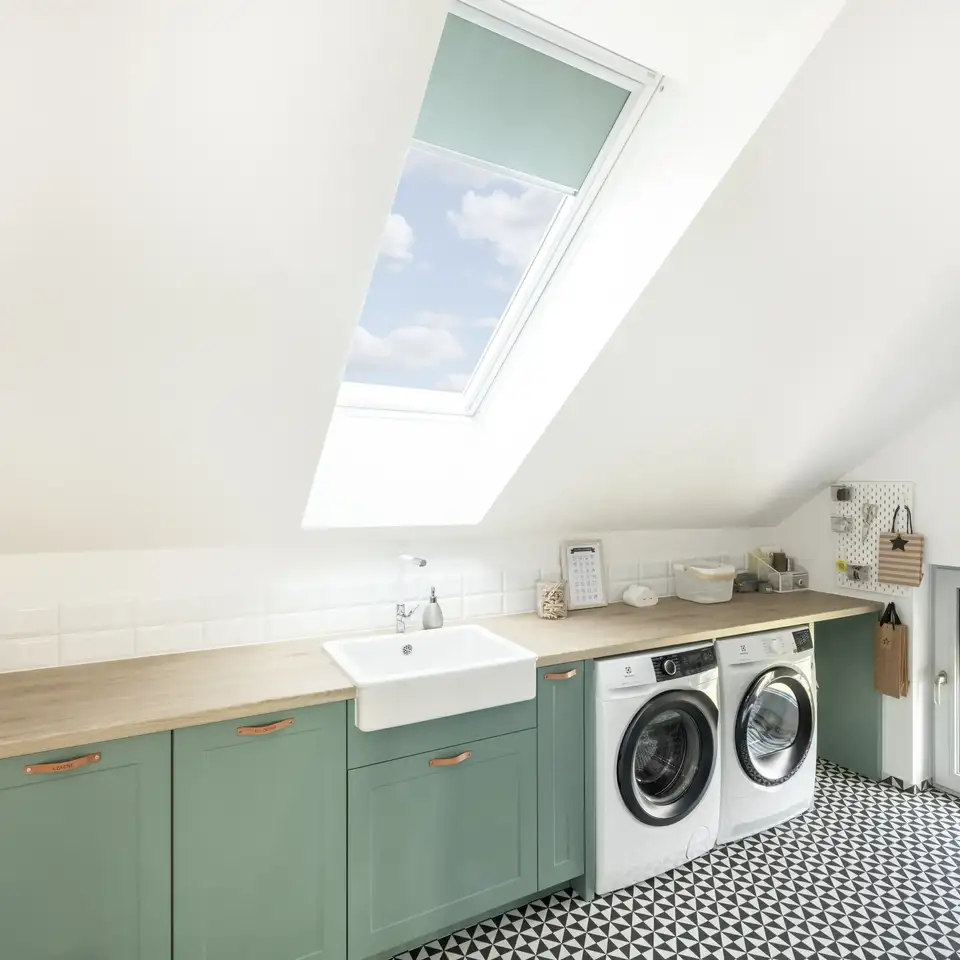 buanderie sous les combles avec meubles bas, vasque, lave-linge et sèche-linge, fenêtre verticale et fenêtre de toit VELUX 