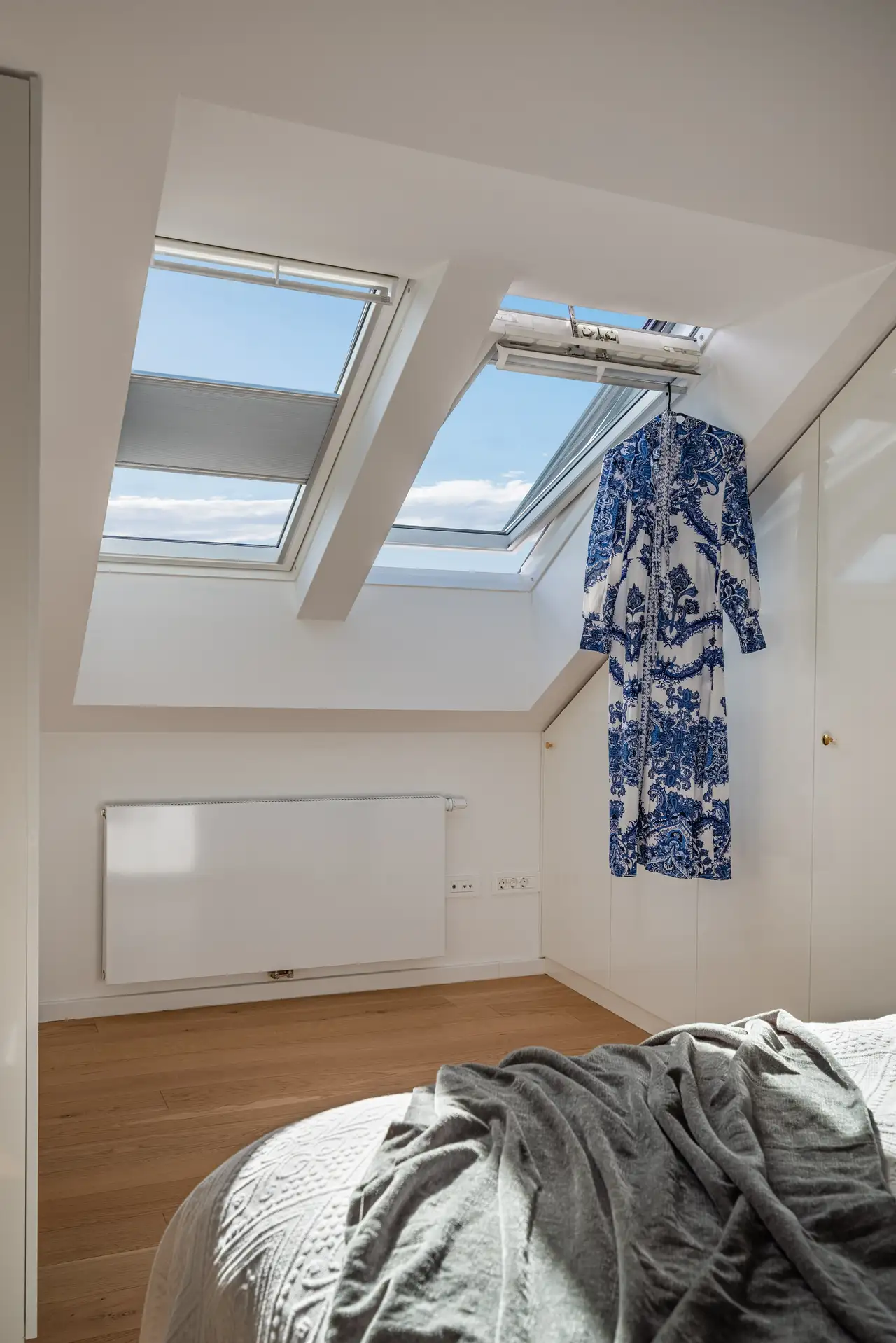 Dormitorio con dos ventanas de tejado VELUX. Una ventana está entreabierta para ventilar. 
