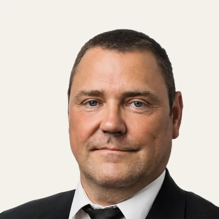 Person in a black suit and tie, wearing a white shirt.