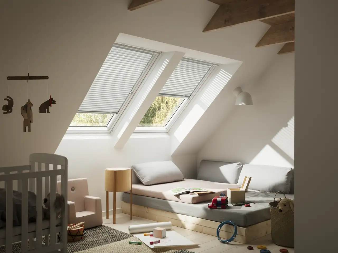 chambre d’enfant avec jouets disposés sur un canapé sous deux fenêtres de toit VELUX équipées de stores vénitiens