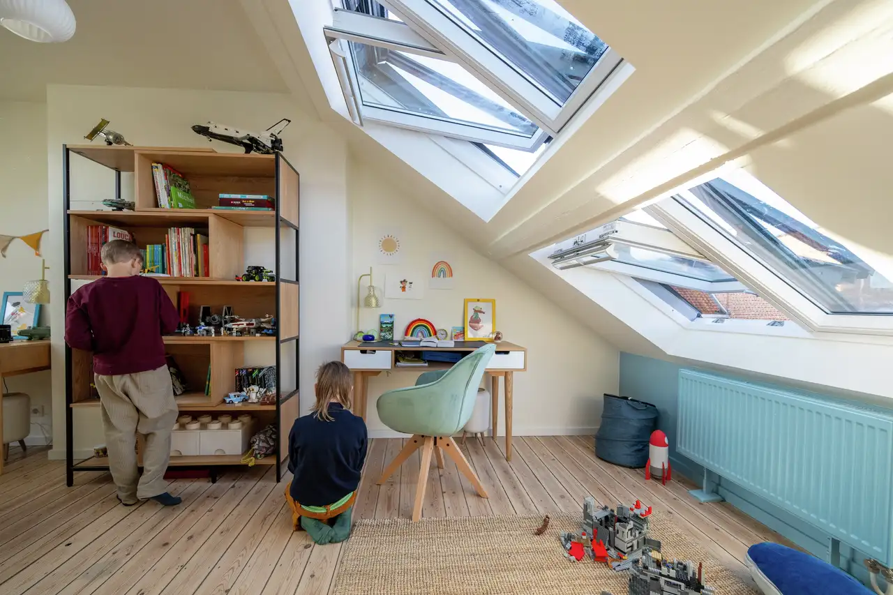 Chambre d’adolescent avec bureau, étagères et fenêtres de toit VELUX superposées ouvertes pour ventiler en hiver.