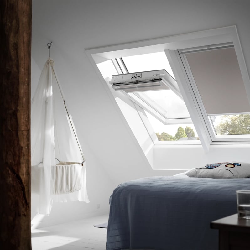 Attic bedroom with sloped ceiling and VELUX roof window, natural light entering.