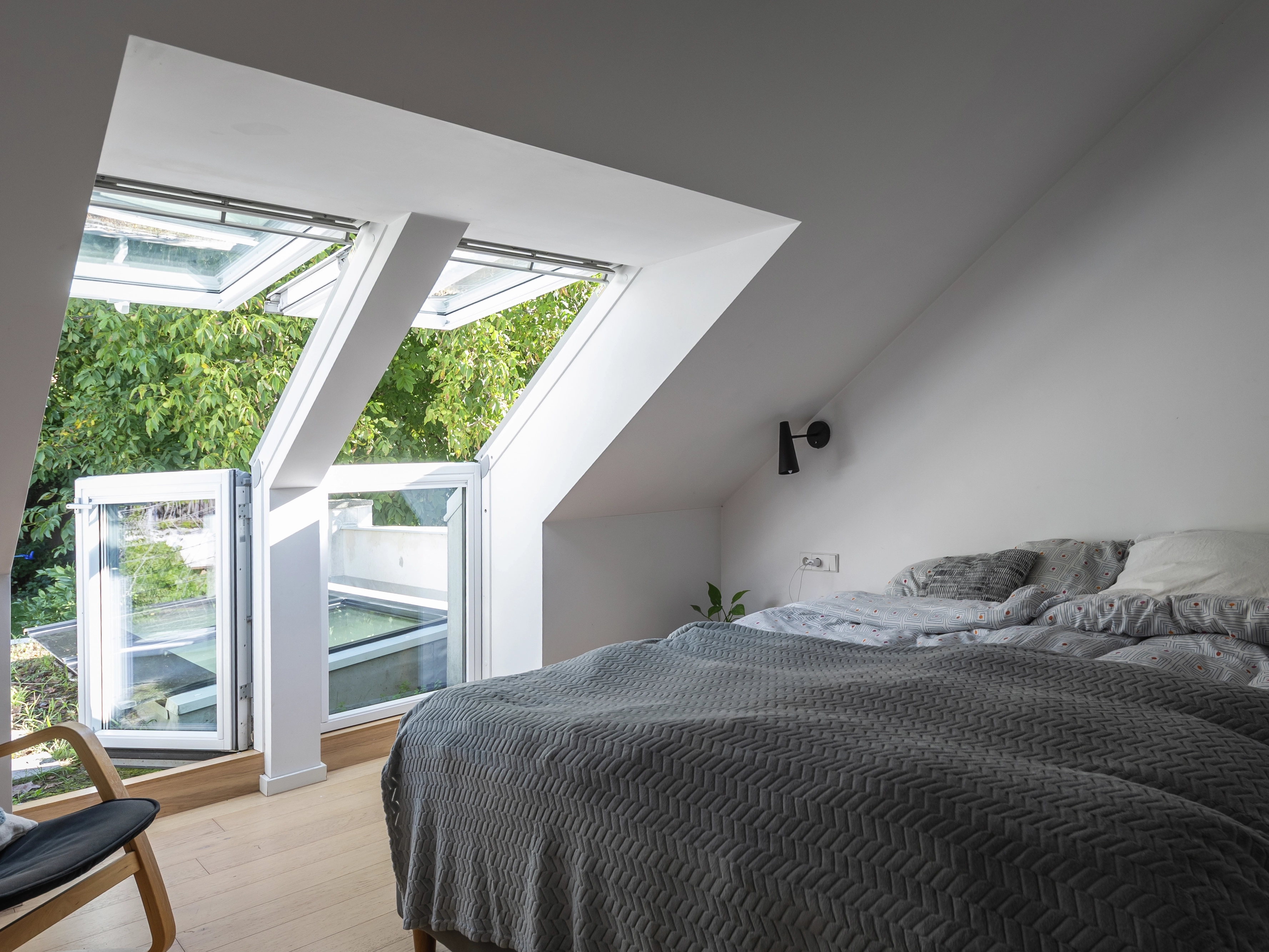 Attic bedroom with sloped ceiling and open VELUX roof window.