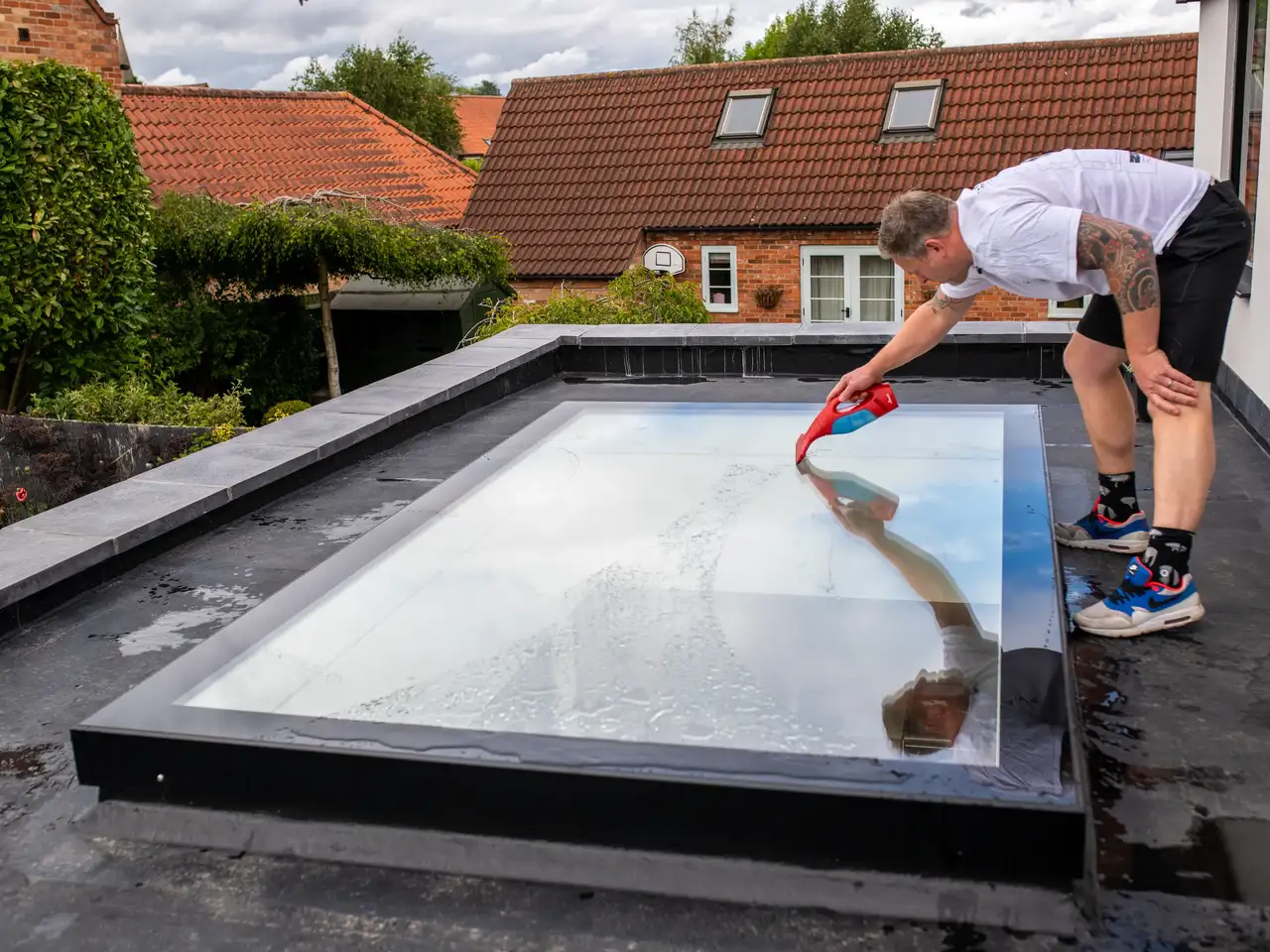Un uomo pulisce la sua finestra per tetti piani dall'esterno | Rivista VELUX