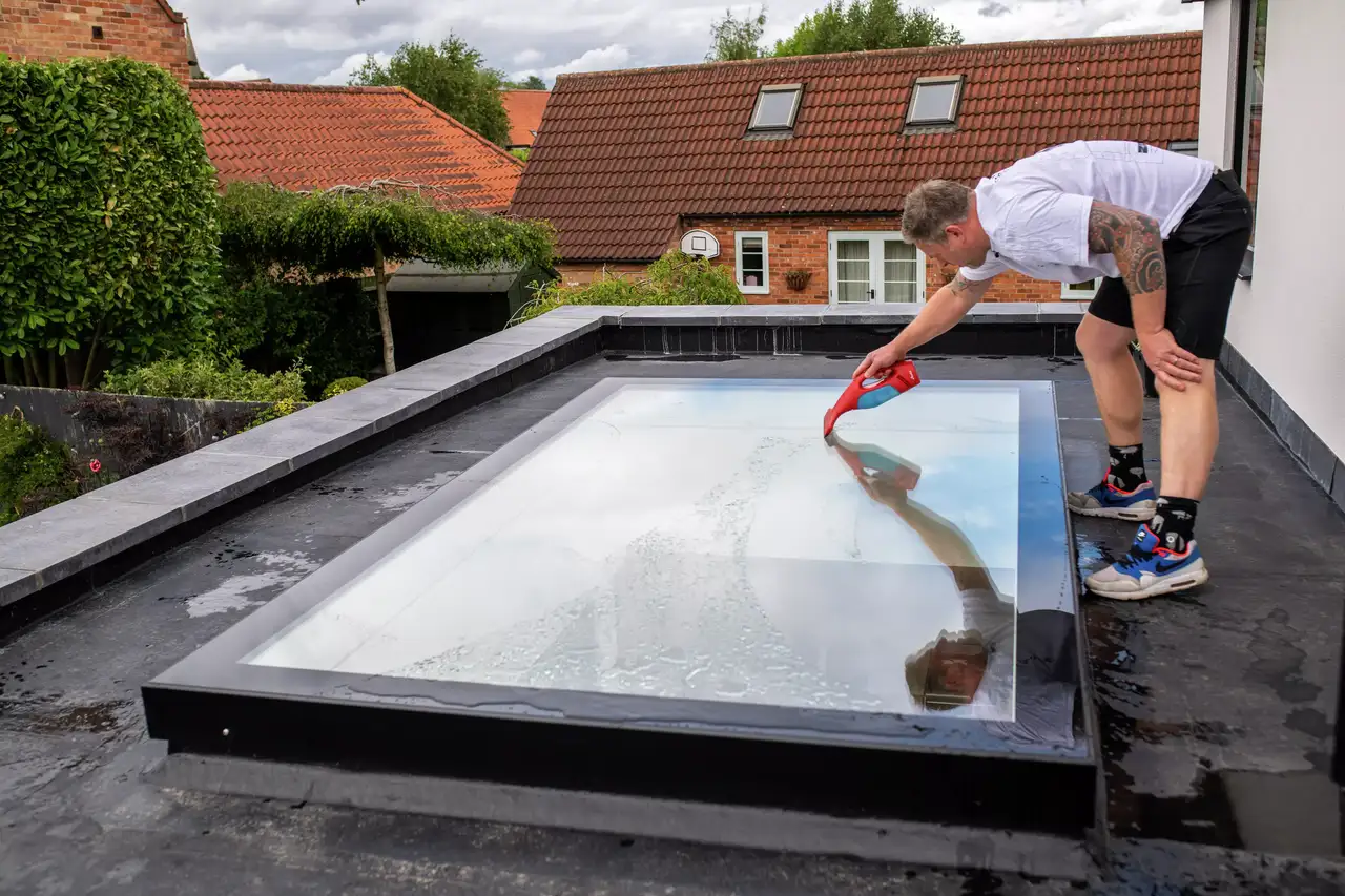 Mann putzt Flachdach-Fenster von außen | VELUX Magazin