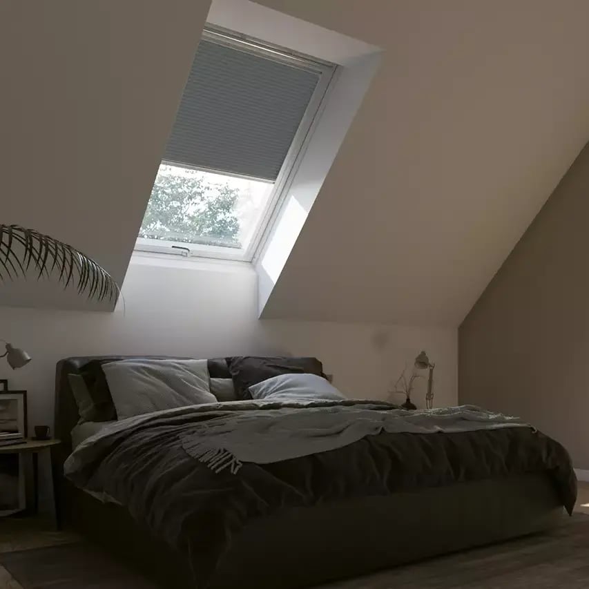 Attic bedroom with sloped ceiling and VELUX roof window, cozy and inviting.