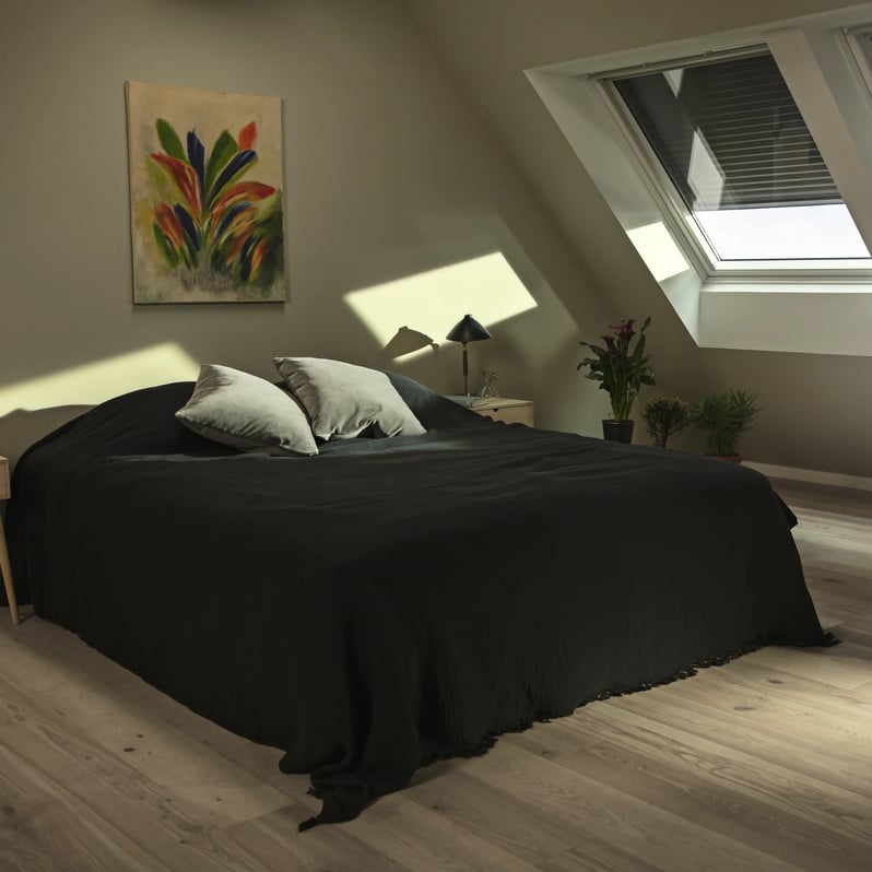 Attic bedroom with sloped ceiling and VELUX roof window, natural light entering.