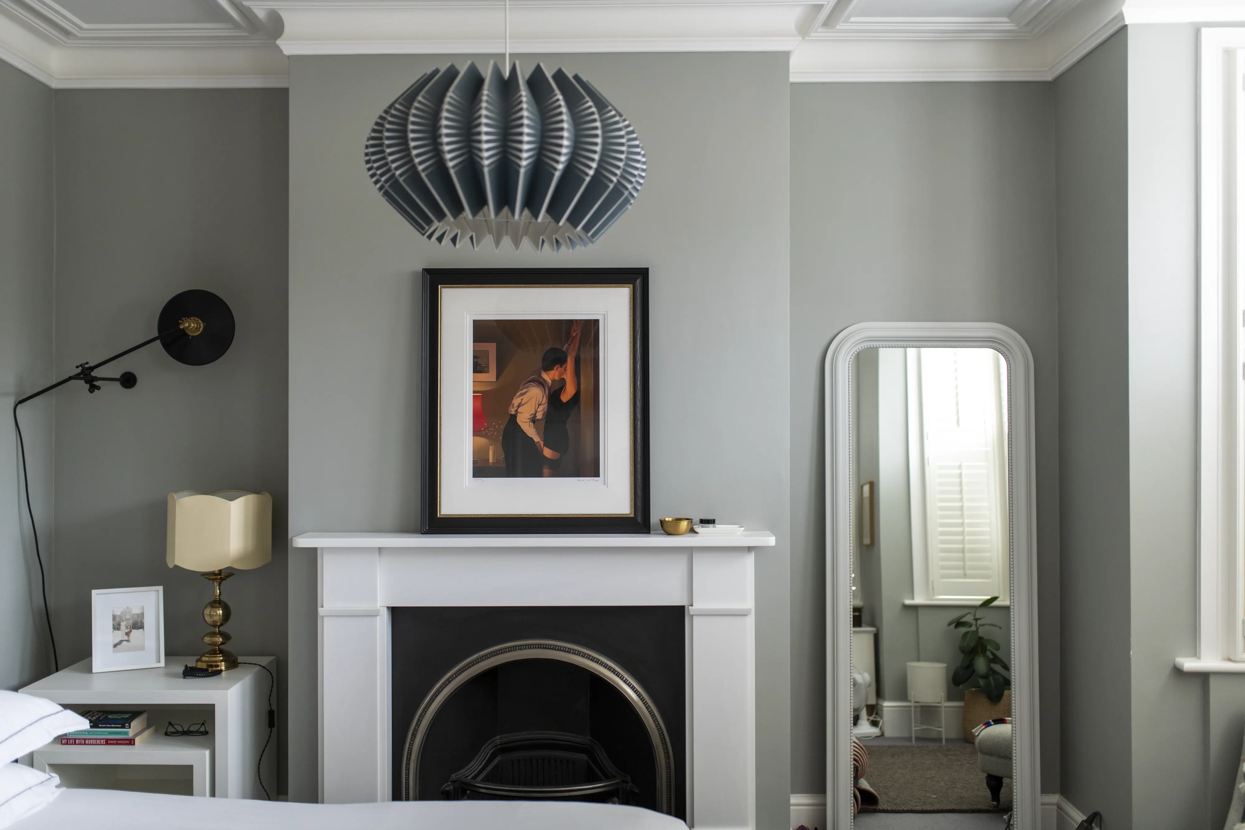 Bedroom with fireplace, modern pendant light, and large mirror.