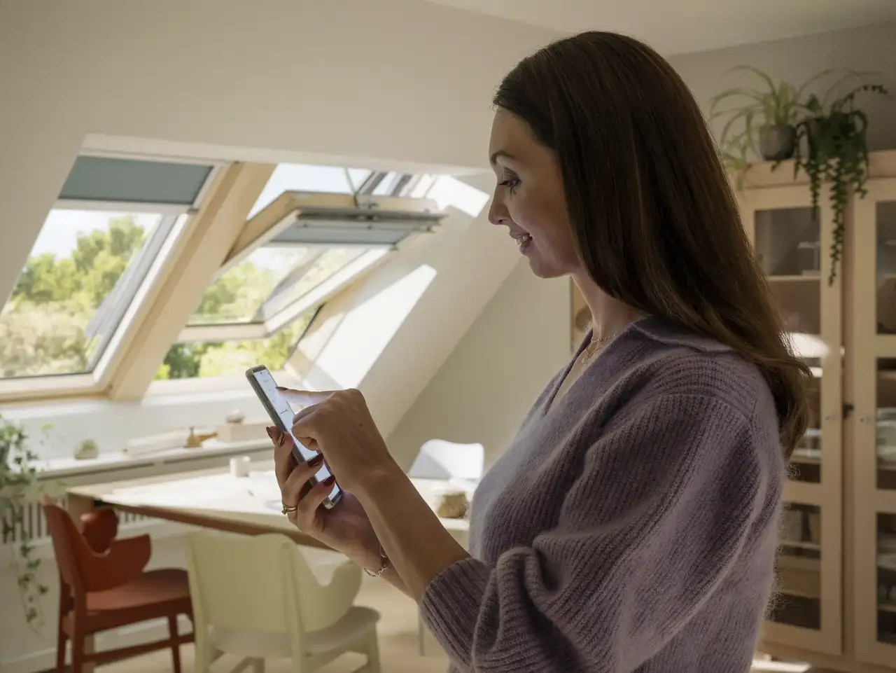 Una donna controlla finestre per tetti e tende dal suo smartphone