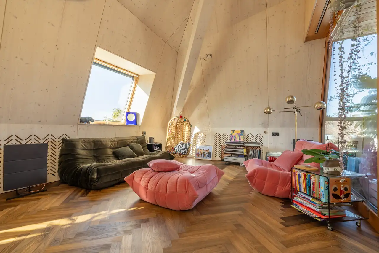 Potkrovlje sa kosim stropom, VELUX krovnim prozorom, udobnim sjedećim garniturama i drvenim podom.