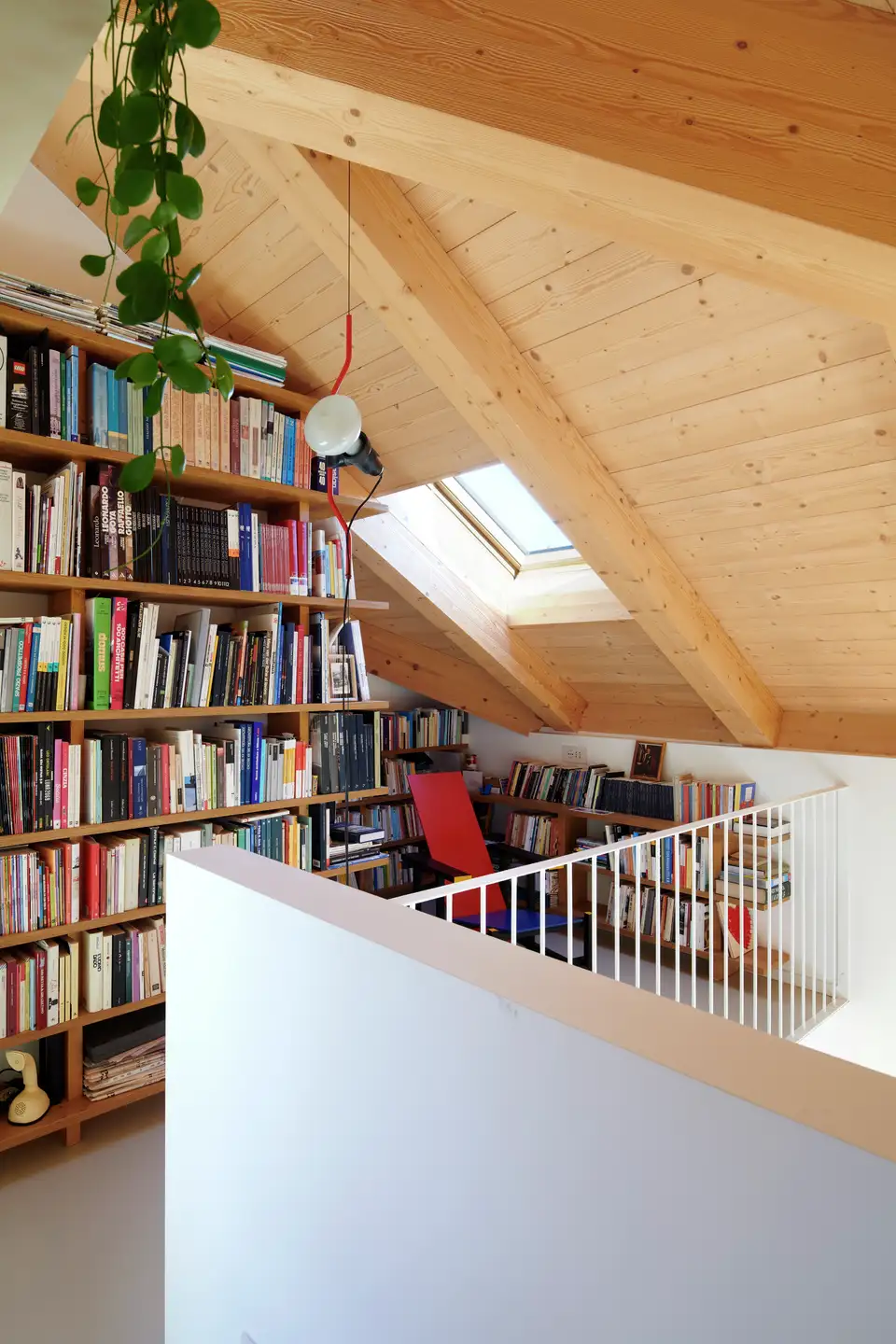 Bibliothèque murale sous combles éclairée par une fenêtre de toit VELUX. 