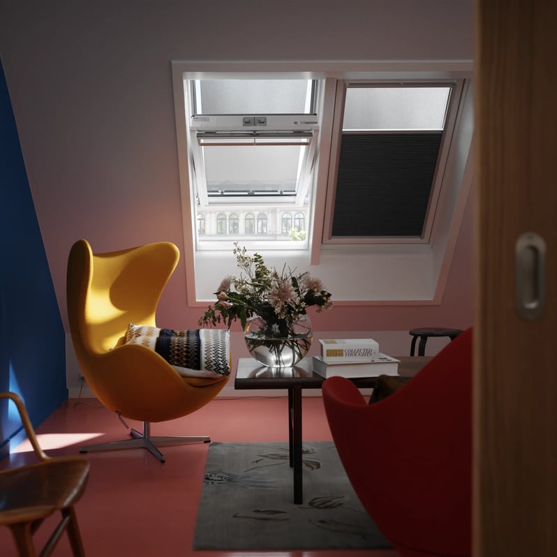 Attic lounge with vibrant furniture and VELUX roof window, natural light entering.