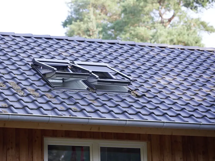 Notranji pogled na strešno okno z zunanjim senčilom VELUX, ki mehča sončno svetlobo in hkrati omogoča nemoten pogled na zunanjost.
